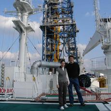 Michael Strasser und France Girault an Bord der Chikyu. Im Hintergrund der Bohrturm 