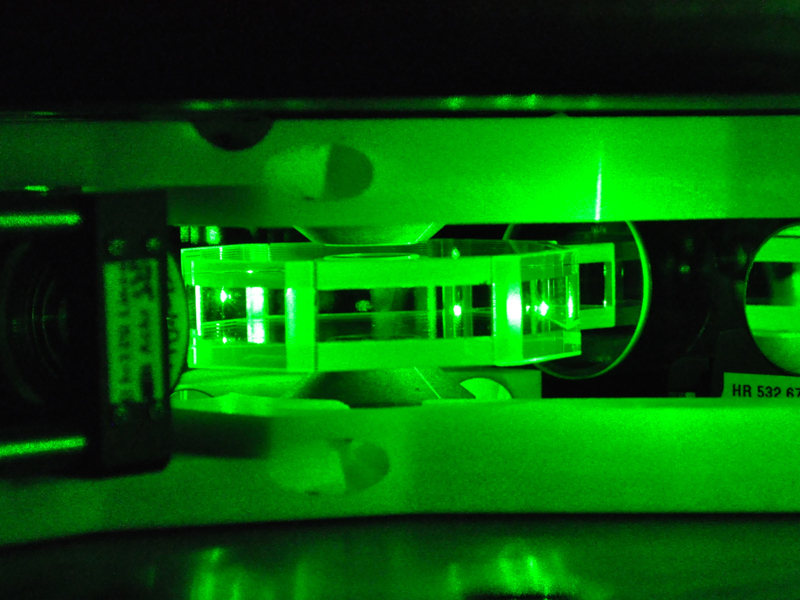 Glaszelle, in der Atome eingefangen warden. Die Atome werden mit Lasern gekühlt. Mit den auf dem Bild sichtbaren grünen Laserstrahlen wird eine Struktur geschaffen, innerhalb der sich die Atome bewegen und so das Verhalten von Elektronen in einem Material nachbilden können. (Bild: Jakob Meineke / ETH Zürich)